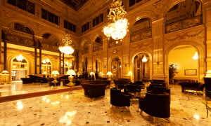 Opulent hotel lobby with marble floors, velvet armchairs, crystal chandeliers, and AI‑driven smart lighting, showcasing AI in Hospitality–powered guest personalization.